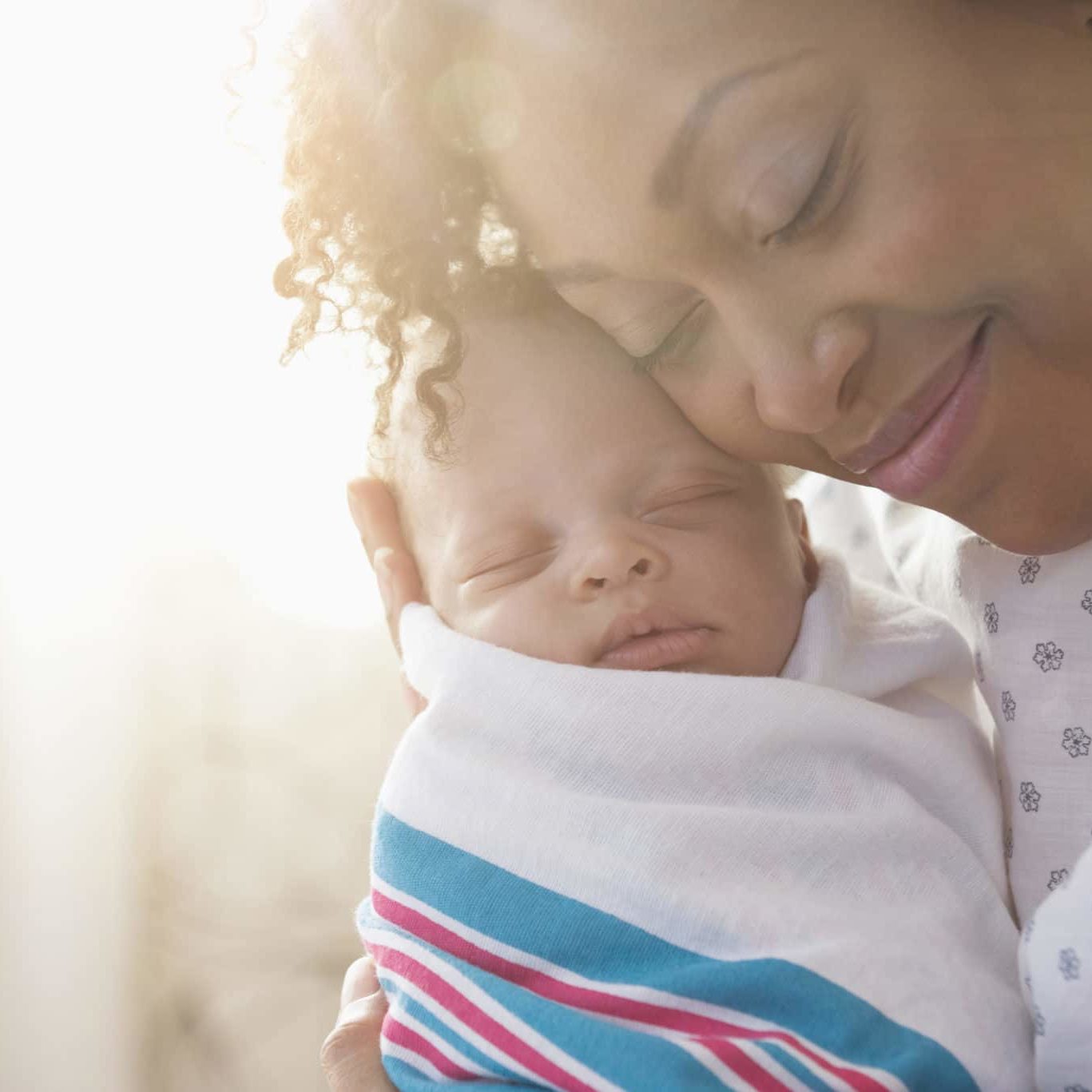 Mixed race mother cradling newborn baby